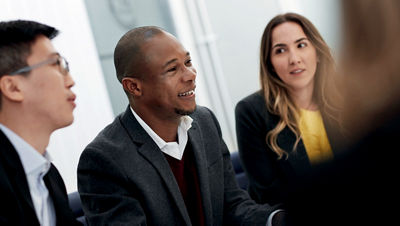 A group of colleagues sit closely together engaged in conversation.